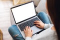 A woman working and typing on laptop computer with blank screen while sitting on a sofa at home Royalty Free Stock Photo