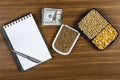 Top view mockup of open blank notebook on spiral, automatic pen. 100 dollar banknotes and samples of soybean, corn and wheat seeds