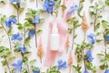 Top view of mockup of unbranded white plastic spray bottle, blue and pink flowers on a white background. Bottle for branding