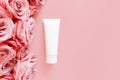 Top view of mockup of white squeeze bottle plastic tube and pink roses on a pastel pink background. Bottle for branding and label