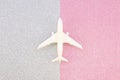 Top view model air plane toy on a silver and pink glitter paper background. Travel minimal flat lay