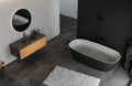 Top view modern bathroom with concrete floor, black bathtub, and oval mirror, marble basin, pendant light, cactus, top view. Royalty Free Stock Photo