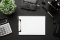 Top view of modern black office desk with blank paper sheet, notebook, pen and a lot of things. Flat lay table layout. Copy space Royalty Free Stock Photo