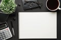 Top view of modern black office desk with blank paper sheet, notebook, pen and a lot of things. Flat lay table layout. Copy space Royalty Free Stock Photo