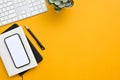 Top view of a modern office desk in yellow background with smartphone white screen mockup Royalty Free Stock Photo