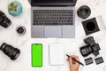 Top view of modern white marble desk of photographer writing in note pad with mobile with green screen chroma key for copy space Royalty Free Stock Photo