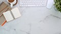 Top view modern workplace with notebook, keyboard, coffee cup and house plant on marble background. Royalty Free Stock Photo