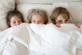 Top view mother and two adorable daughters peeking from blanket