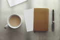 Top view of a mug with coffee, a notebook, a pen and blank paper on a wooden desk table next to a window. Empty copy space Royalty Free Stock Photo