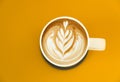 view of a mug of latte art coffee isolted on yellow background