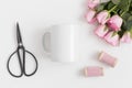 Top view of a mug mockup with a bouquet of pink roses and silk ribbons on a white table