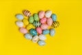 Top view of multicolored festive eggs in shape of heart. Easter eggs on yellow background