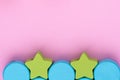 Top view on multicolored kids toys on light pink paper background. Wooden green stars, blue circles. Copy space for text Royalty Free Stock Photo