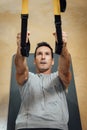 Top view of muscular man doing pull up exercise with suspension equipment at gym Royalty Free Stock Photo