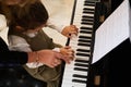 Top view music teacher, pianist holding the hands of a child girl, teaching piano lesson showing correct finger position