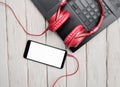 Top view musical red overhead headphones on pc keyboard. Audio music headphones with laptop and with smartphone with white display Royalty Free Stock Photo