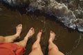 Top view on naked feets on sand in foaming sea wave. Royalty Free Stock Photo