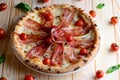 Top view of neapolitan pizza with bacon, mozzarella and cherry tomatoes, served on a wooden table. Italy food. Close up.