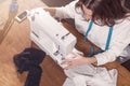 Top view of needlewoman stitching fabric on sewing machine at workplace in studio