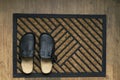 Top view of new doormat and black house slippers on the wooden floor Royalty Free Stock Photo