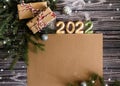 Top view New Year greeting card with copy space. Craft gifts, branches of christmas tree and zirphra 2022 on dark wooden Royalty Free Stock Photo