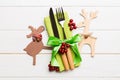 Top view of new year utensils on napkin with holiday decorations and reindeer on wooden background. Christmas dinner concept with Royalty Free Stock Photo