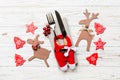 Top view of new year utensils on napkin with holiday decorations and reindeer on wooden background. Close up of christmas dinner Royalty Free Stock Photo