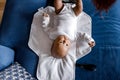 Top view of newborn Afro American baby boy looking at camera and laying with blanket on sofa, while mother changes Royalty Free Stock Photo