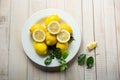 Top view of a nicely decorated white plate of whole and sliced lemons and lemon tree leaves Royalty Free Stock Photo