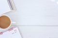 Top view note book, calendar and coffee cup on white wooden table