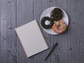 Top view of Notebook, ballpen, and doughnut on wooden background Royalty Free Stock Photo