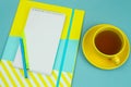 notebook with blank white paper sheet, pencilsand cup of tea on a blue background Royalty Free Stock Photo