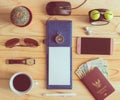 Top view of notebook, pen, sunglasses, coffee cup, passport, mon