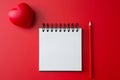 Top view of Notebook, pencil, heart shaped ball on a red background and copy space