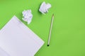 Top view of notebook with pencil and white crumpled paper ball on green background. Concept of no idea, education, minimalism. Royalty Free Stock Photo