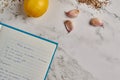 Top view of a notebook with a recipe, lemon, and garlic on a marble table