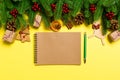 Top view of notebook on yellow background made of Christmas decorations. New Year time concept
