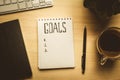 Top view of notepad with Goals List, cup of coffee on wooden table, goals concept Royalty Free Stock Photo