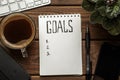 Top view of notepad with Goals List, cup of coffee on wooden table, goals concept Royalty Free Stock Photo