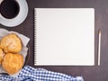 The top view of a notepad with a pencil, choux cream on a plate, and a white coffee cup on a table. Royalty Free Stock Photo