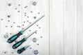 Top view of nuts and three screwdrivers situated diagonally on wooden DIY workbench Royalty Free Stock Photo