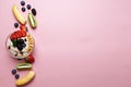 Top view of oatmeal plate with fruit and berries on pink pastel background with copy space