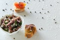 Top view of octopus salad with slices of toasted baguette - bruschetta on white background with black pepper and sea salt. Royalty Free Stock Photo