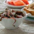 Top view of octopus salad with slices of toasted baguette and tomatoes on rustic wooden background Royalty Free Stock Photo