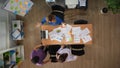 Top view of office boardroom with young men and women workers standing near the desk full of documents and discussing Royalty Free Stock Photo