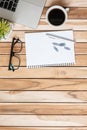 Top view Office desk with blank notebook, pen, paper clips, computer laptop, plant pot, eyeglasses and coffee cup on wood table Royalty Free Stock Photo