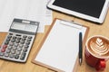 The top view of the office desk blank paper, pen, calculator, tablet, coffee. Financial planning and work concept