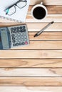 Top view Office desk with calculator, pen, eyeglasses, blank notebook and coffee cup on wood table background. workspace or home Royalty Free Stock Photo