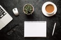 Top view of office desk. Green plant in a pot, cup of coffee, computer mouse, pen, modern silver laptop with blank notepad for Royalty Free Stock Photo