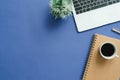 Top view office desk with laptop, notebooks and coffee cup on blue color background. Royalty Free Stock Photo